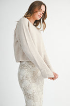 Woman wearing a light taupe sweater and white lace skirt on a white background