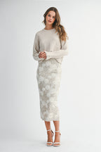 Woman wearing a light taupe sweater and white lace skirt on a white background