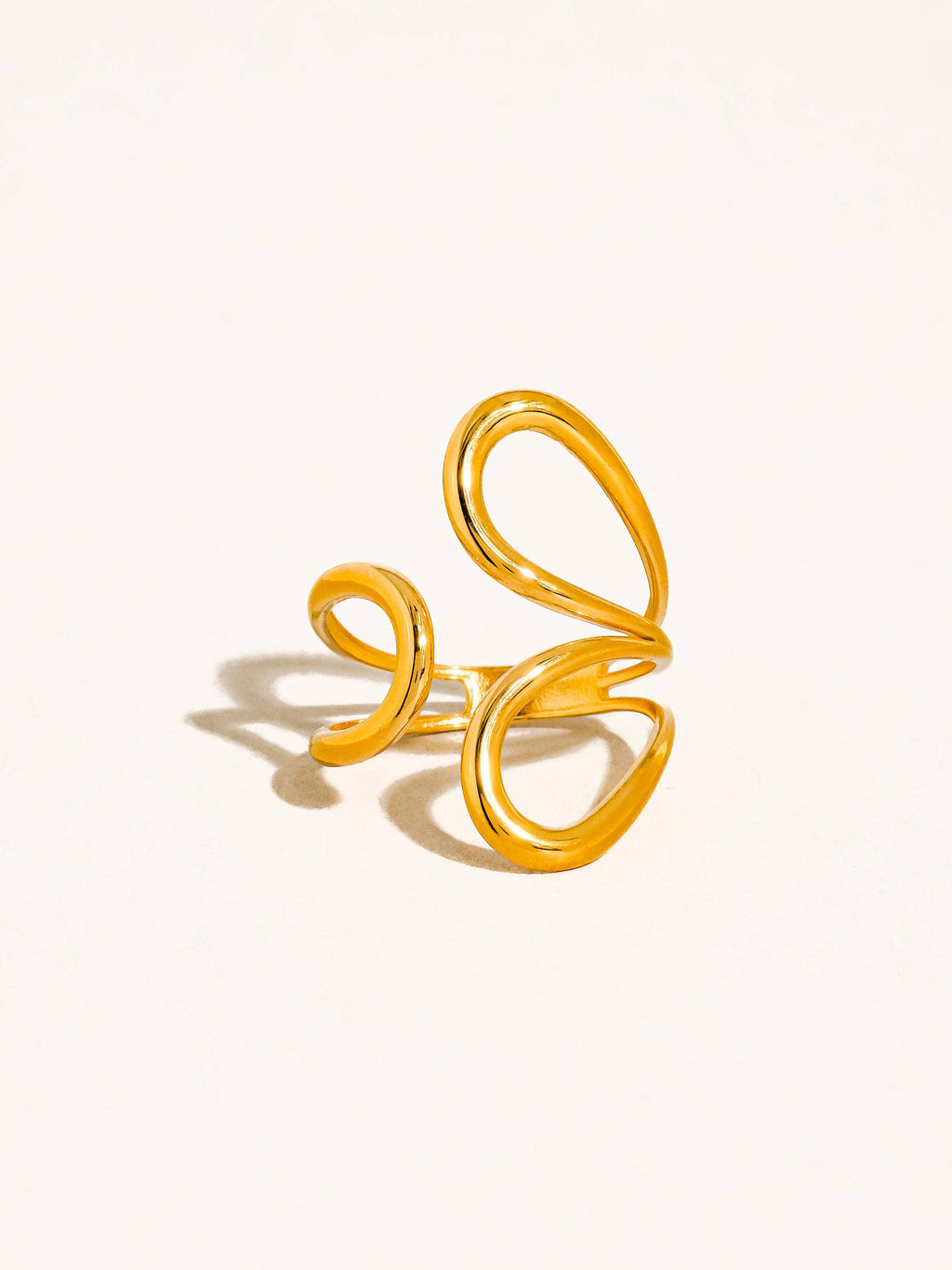 Gold open abstract swirl ring on a light beige background