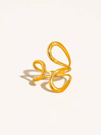 Gold open abstract swirl ring on a light beige background