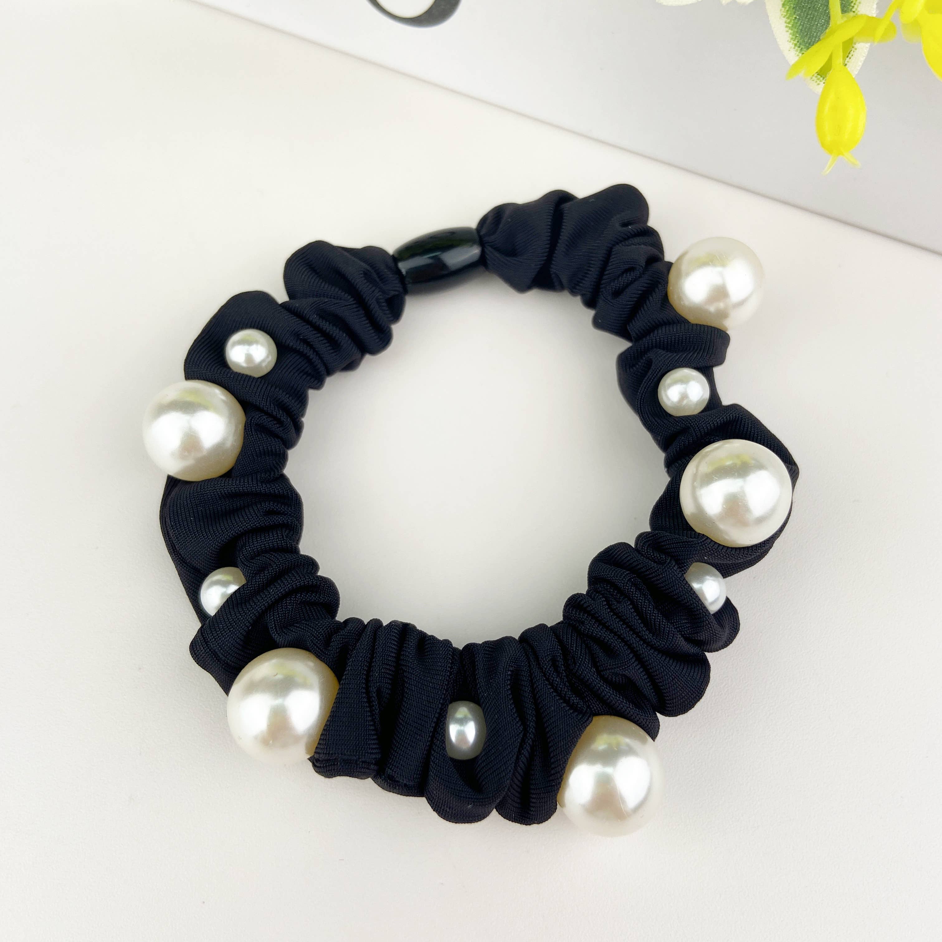 Black scrunchie with pearl embellishments on a white background