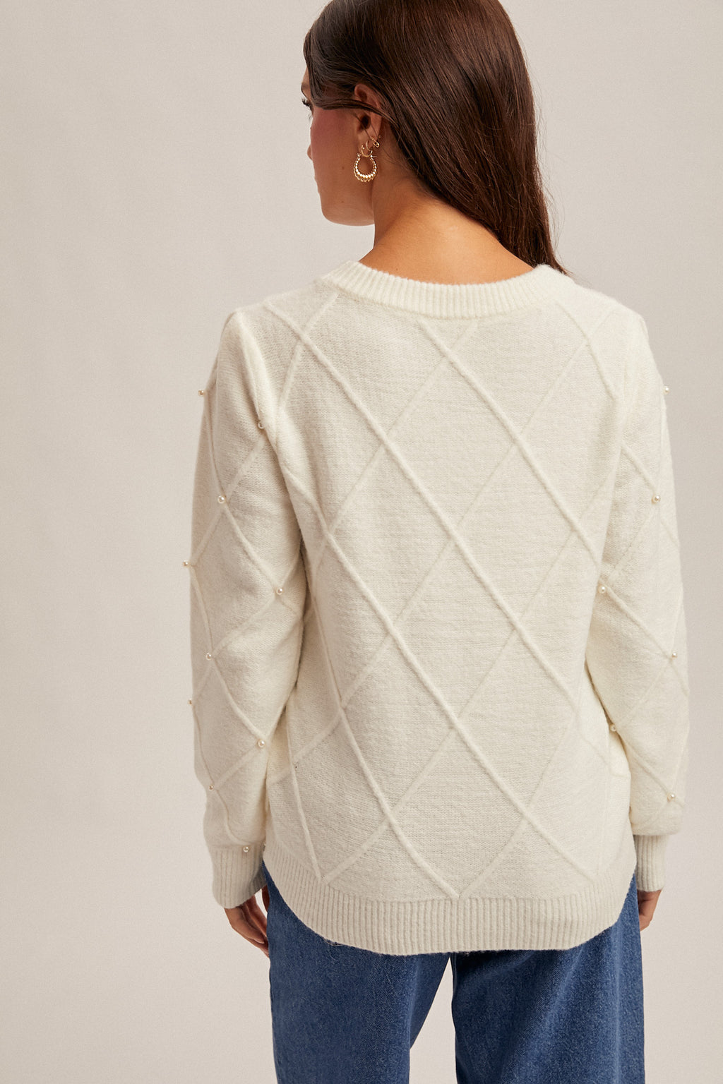 Back view woman wearing diamond design pearl embellishment cream sweater on gray background