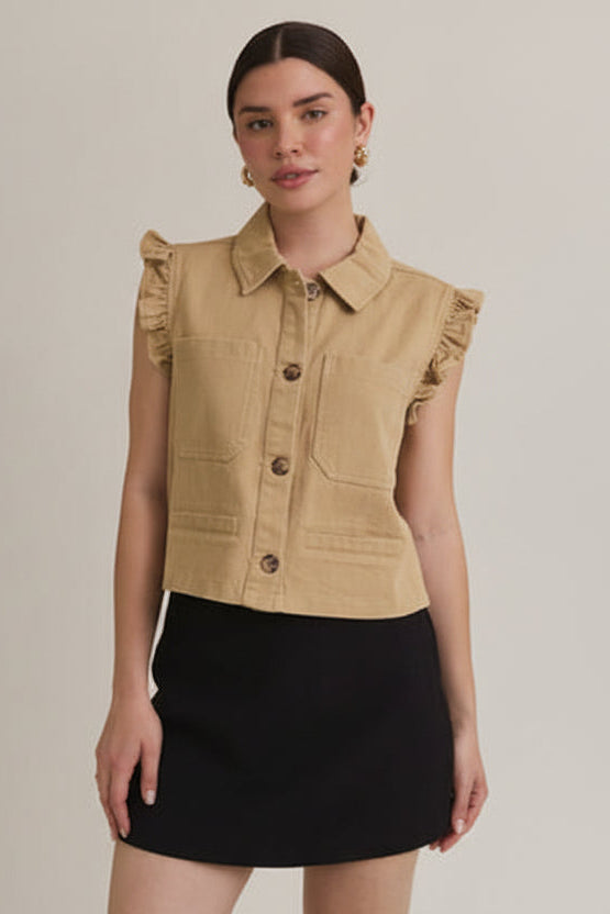 Woman wearing taupe ruffle detail button down collar jean vest with black skirt on beige  background
