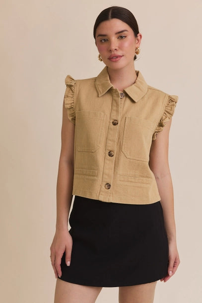 Woman wearing taupe ruffle detail button down collar jean vest with black skirt on beige  background