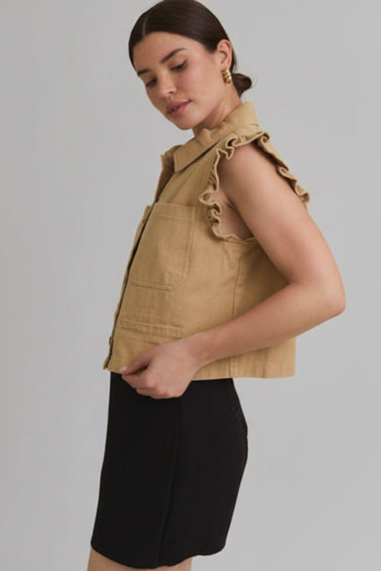 Woman wearing taupe ruffle detail button down collar jean vest with black skirt on beige  background