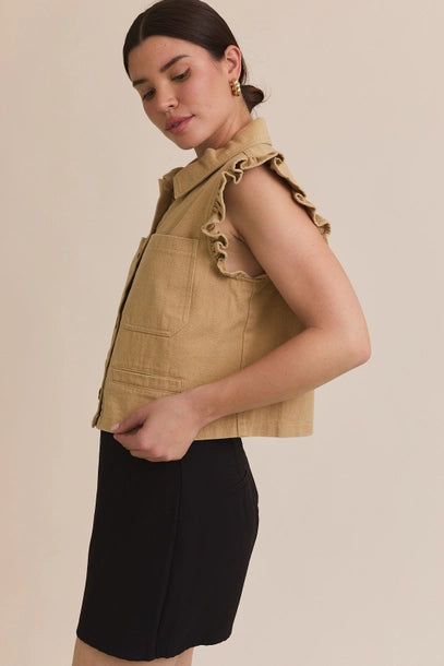 Woman wearing taupe ruffle detail button down collar jean vest with black skirt on beige  background
