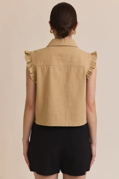 Back view of a woman wearing taupe ruffle detail button down collar jean vest with black skirt on beige  background