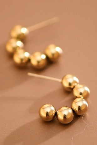 Gold bead post earrings on a brown background