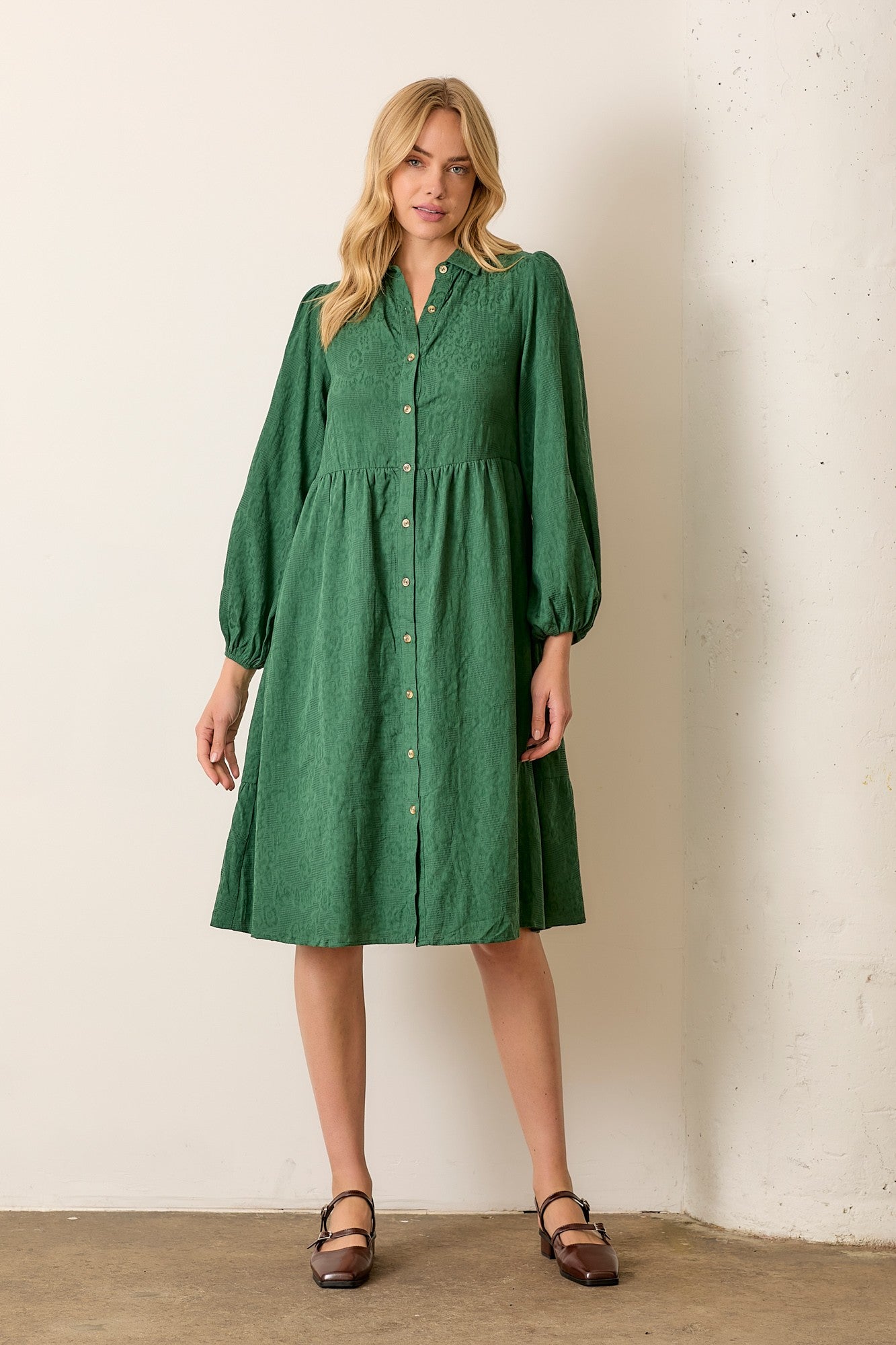 Woman wearing hunter green button front long sleeve midi dress on white background