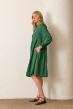 Woman wearing hunter green button front long sleeve midi dress on white background