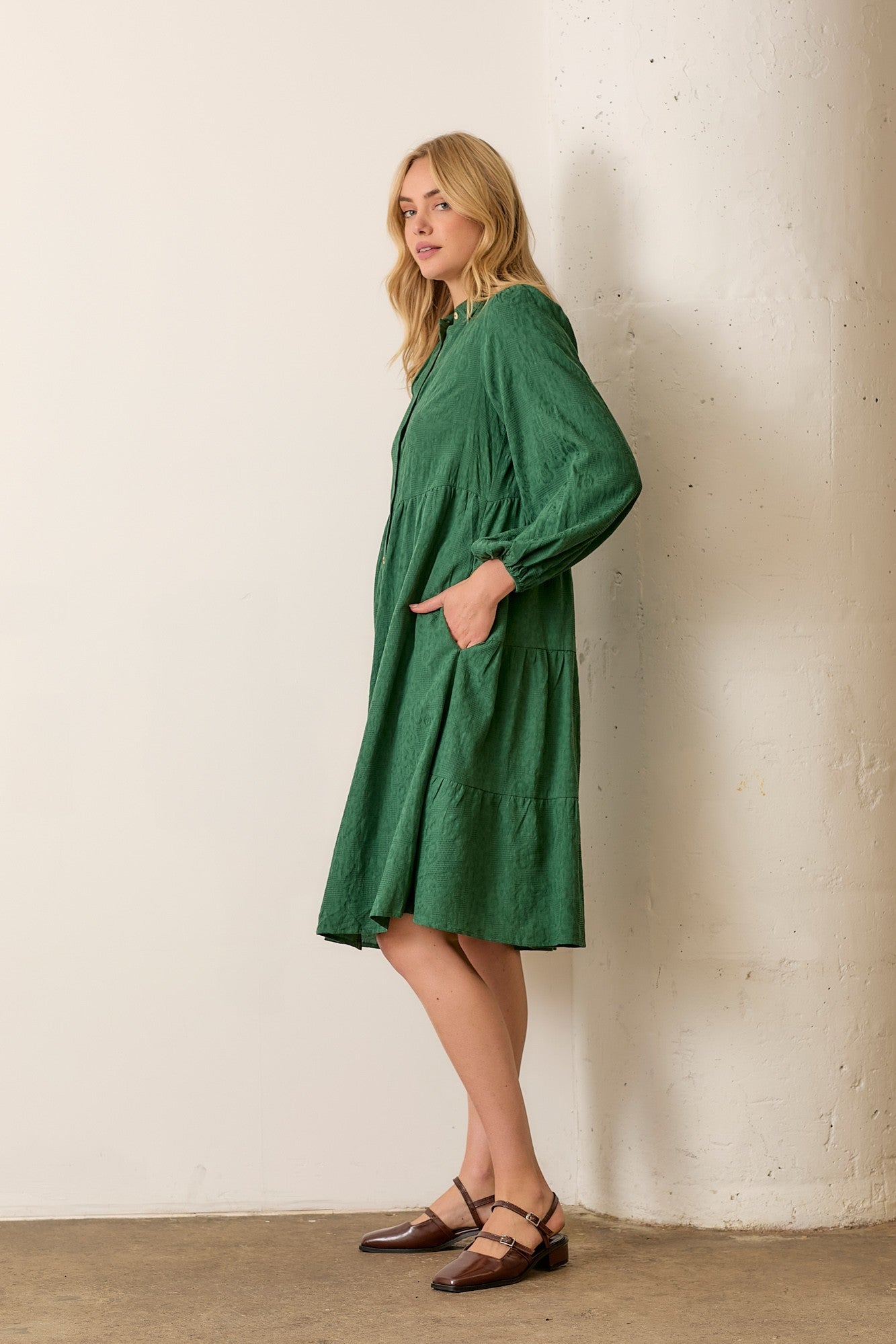 Woman wearing hunter green button front long sleeve midi dress on white background