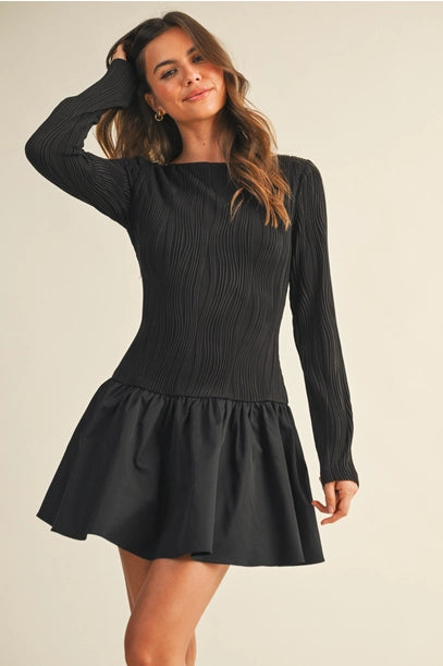 Woman wearing a black long sleeve flare dress on a beige background