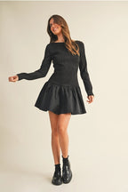 Woman wearing a black long sleeve flare dress on a beige background