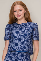 Woman wearing a blue floral top against a plain background