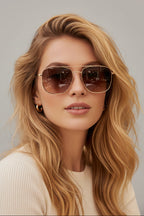 Woman wearing square cream and metal sunglasses in outdoor setting