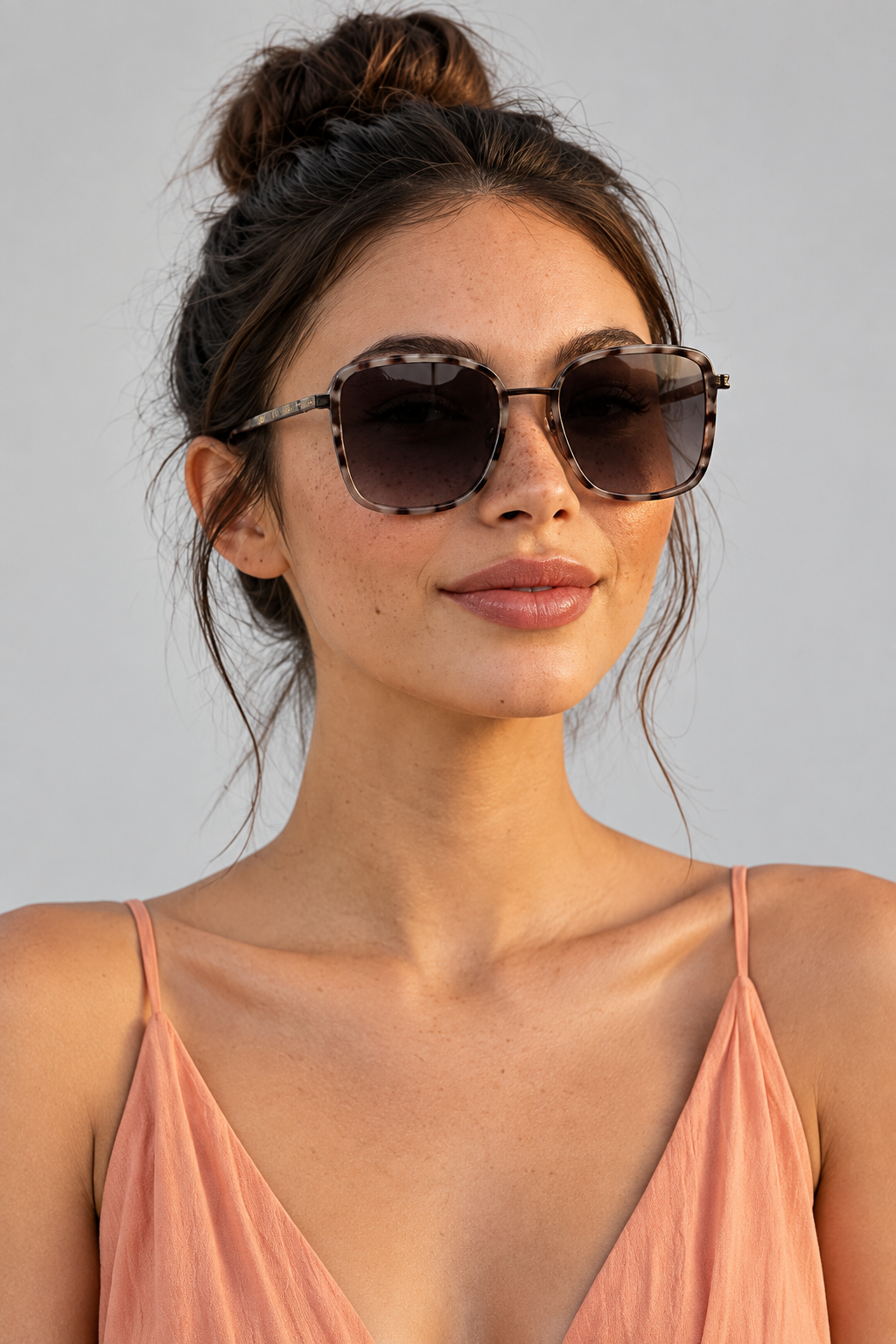 Woman wearing grey cheetah sunglasses and a peach dress at an outdoor event with palm trees and city skyline.