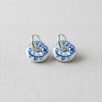 Pair of white hoop earrings with blue floral patterns on a light gray background