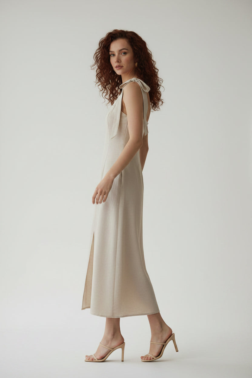 Woman wearing an oatmeal linen blend dress with a slit on a gray background