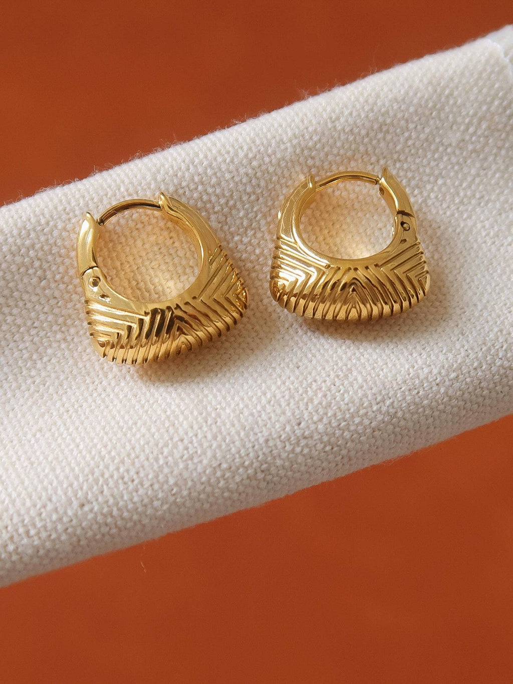 18k gold-plated textured hoop earrings on white surface