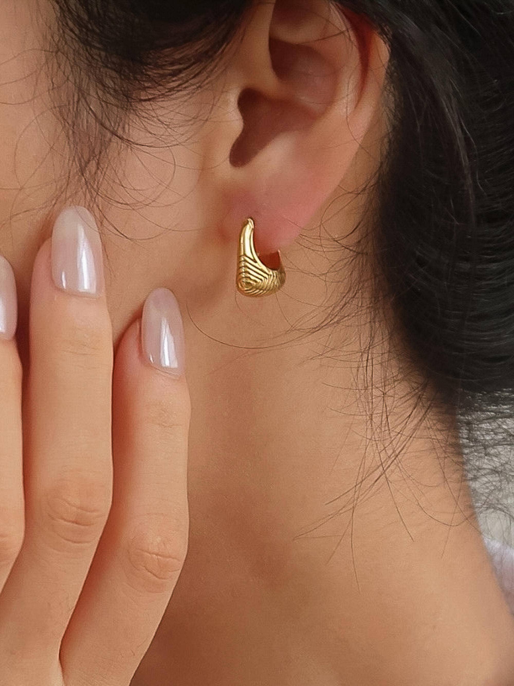 Woman wearing 18k gold-plated textured hoop earrings