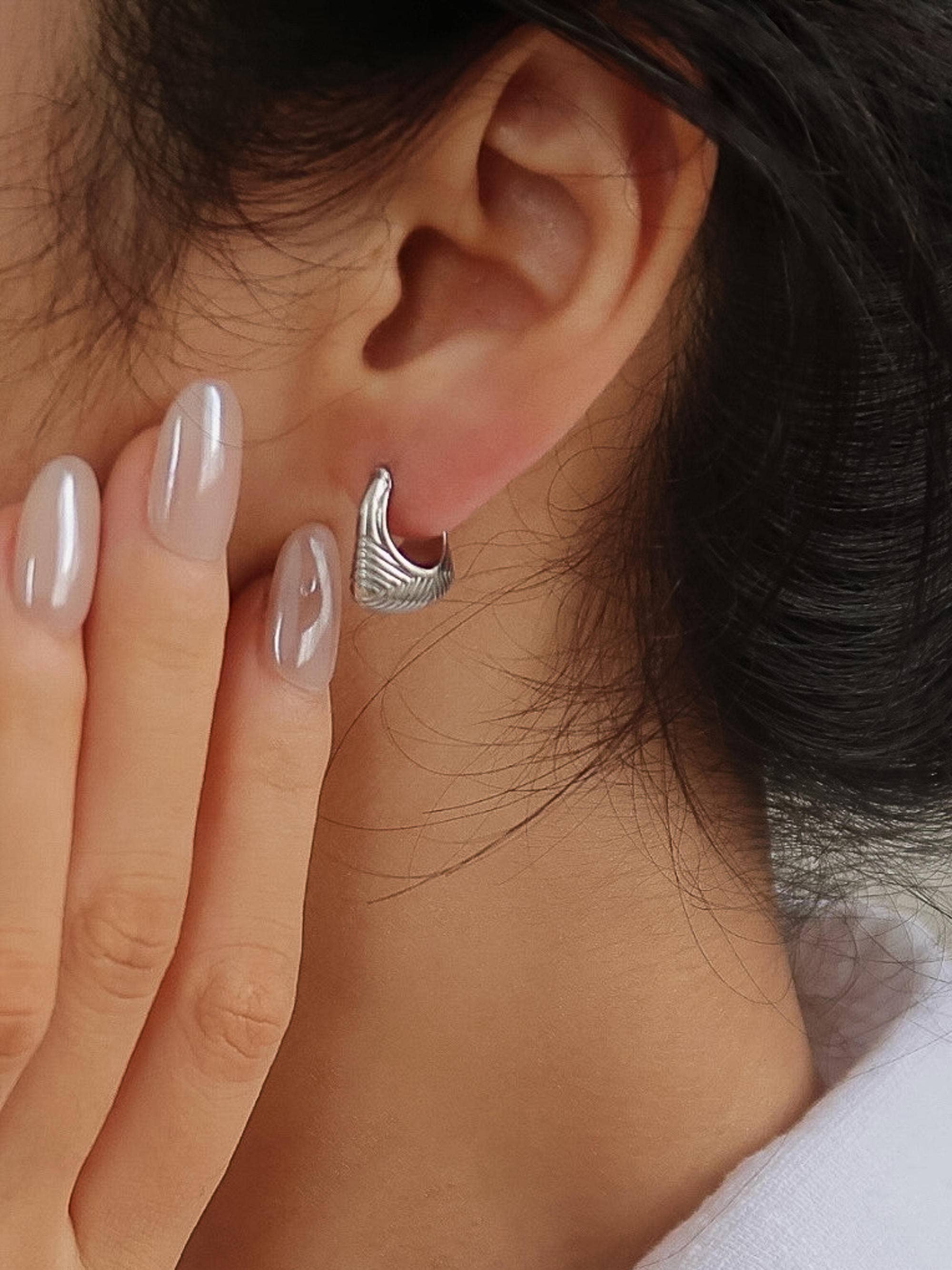 Woman wearing 18k silver-plated textured hoop earrings