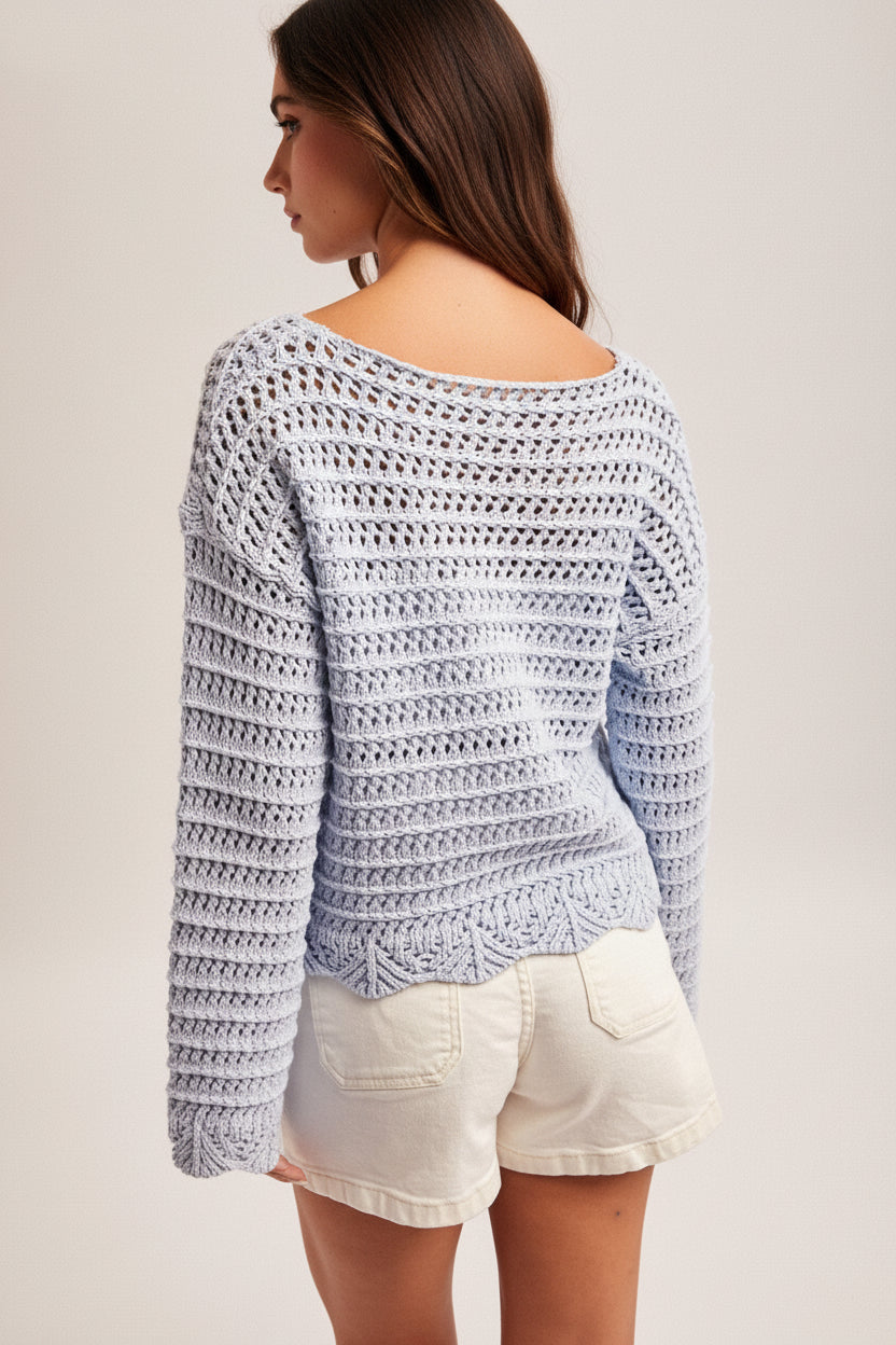 Back view of a woman wearing a sky blue crochet top, white shorts and straw hat on a plain background