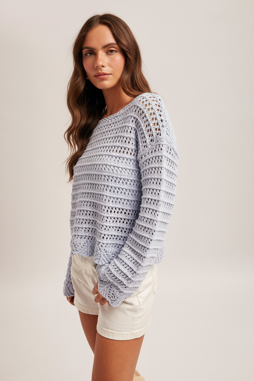 Woman wearing a sky blue crochet top, white shorts and straw hat on a plain background