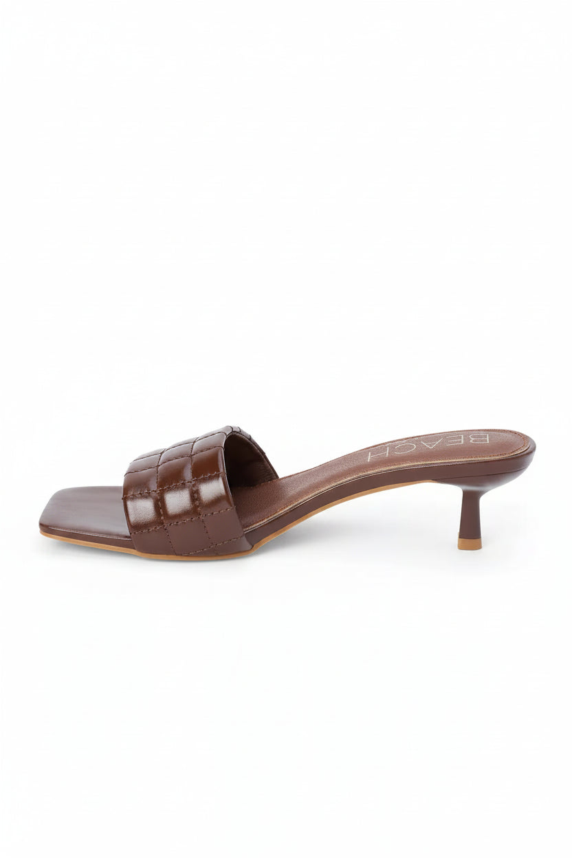 Brown quilted sandal with a small heel on a white background