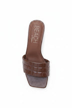 Brown sandal with 'BEACH' branding on a white background