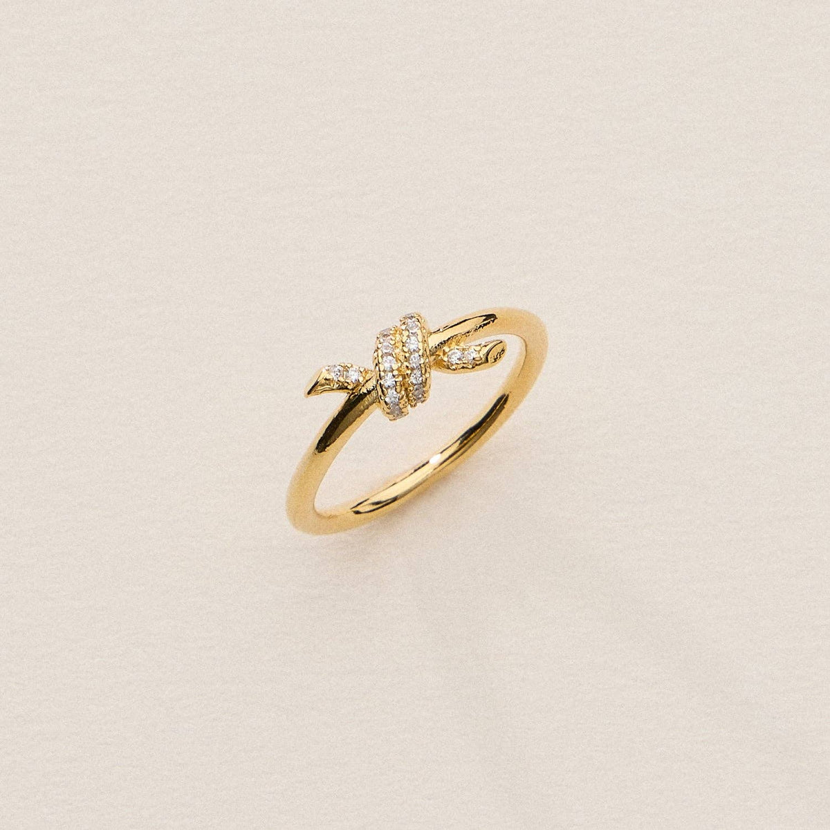 Gold knot ring with pave cubic zirconia detail on a gray background