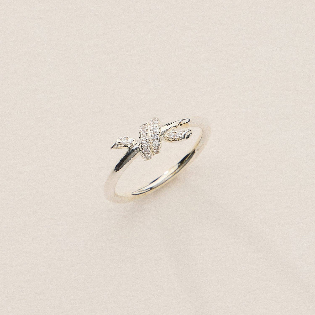 Silver plated knot ring enhanced with pave cubic zirconia on a gray background