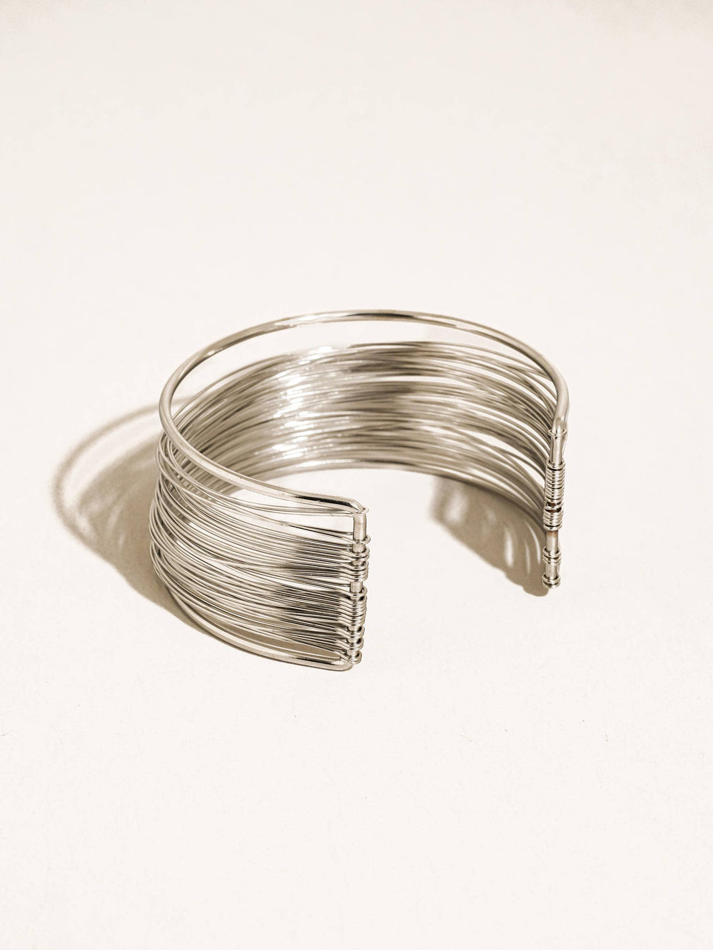 Silver wire cuff bracelet on a light beige background