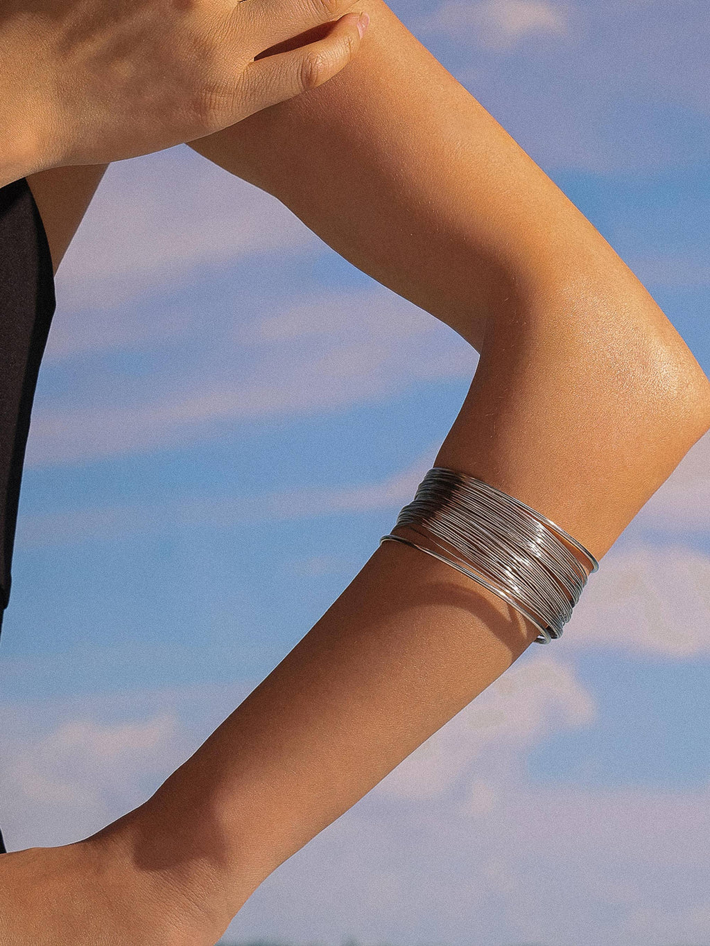 Silver bracelet on a wrist with a blue sky background