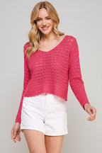 Woman wearing a hot pink crochet top and white shorts on a beige background