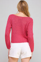 Back view of a woman wearing a hot pink crochet top and white shorts on a beige background