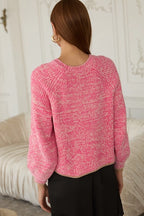 Back view of a woman wearing a pink chenille knitted sweater against a white background