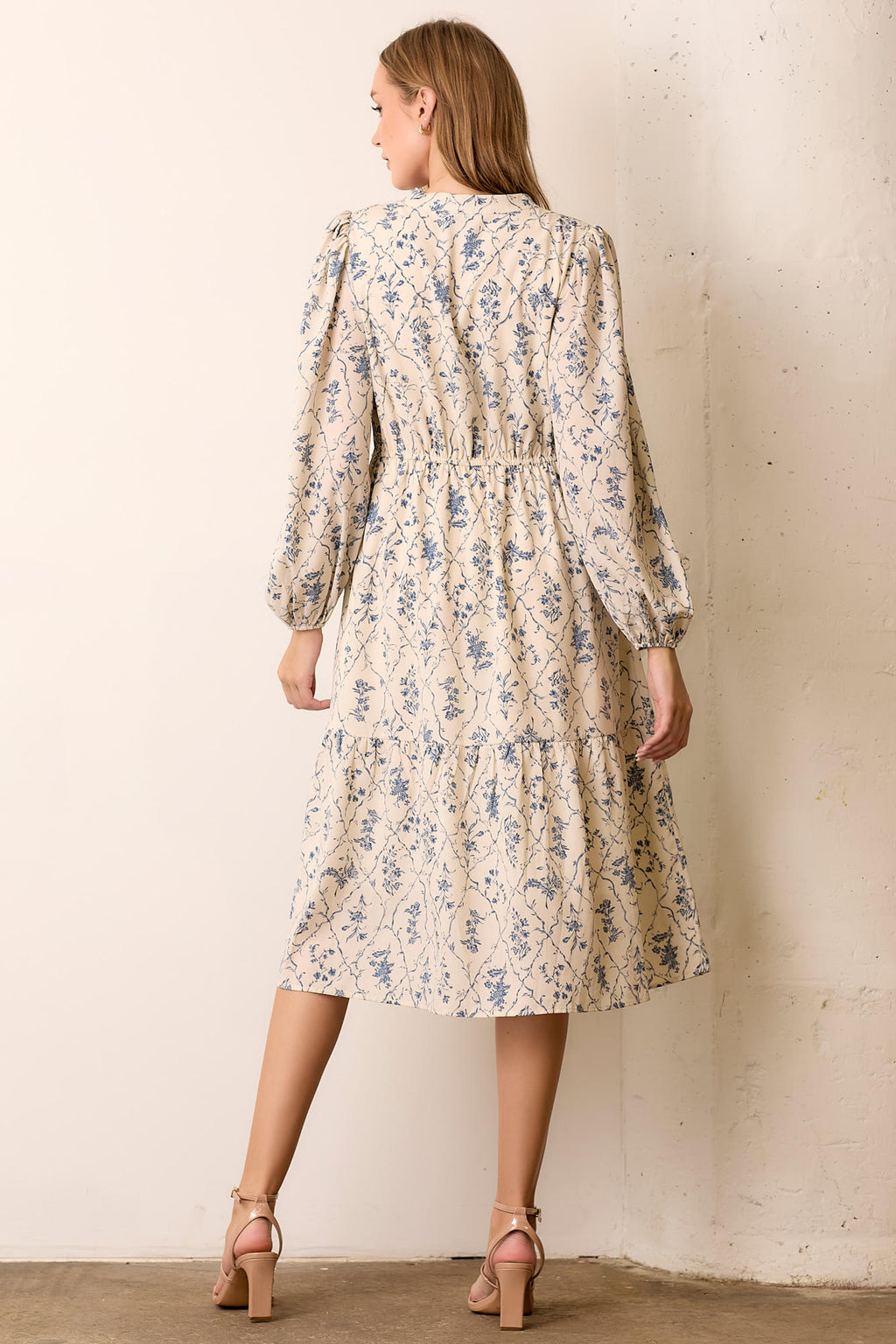 Back view of woman wearing floral maxi dress against a white background