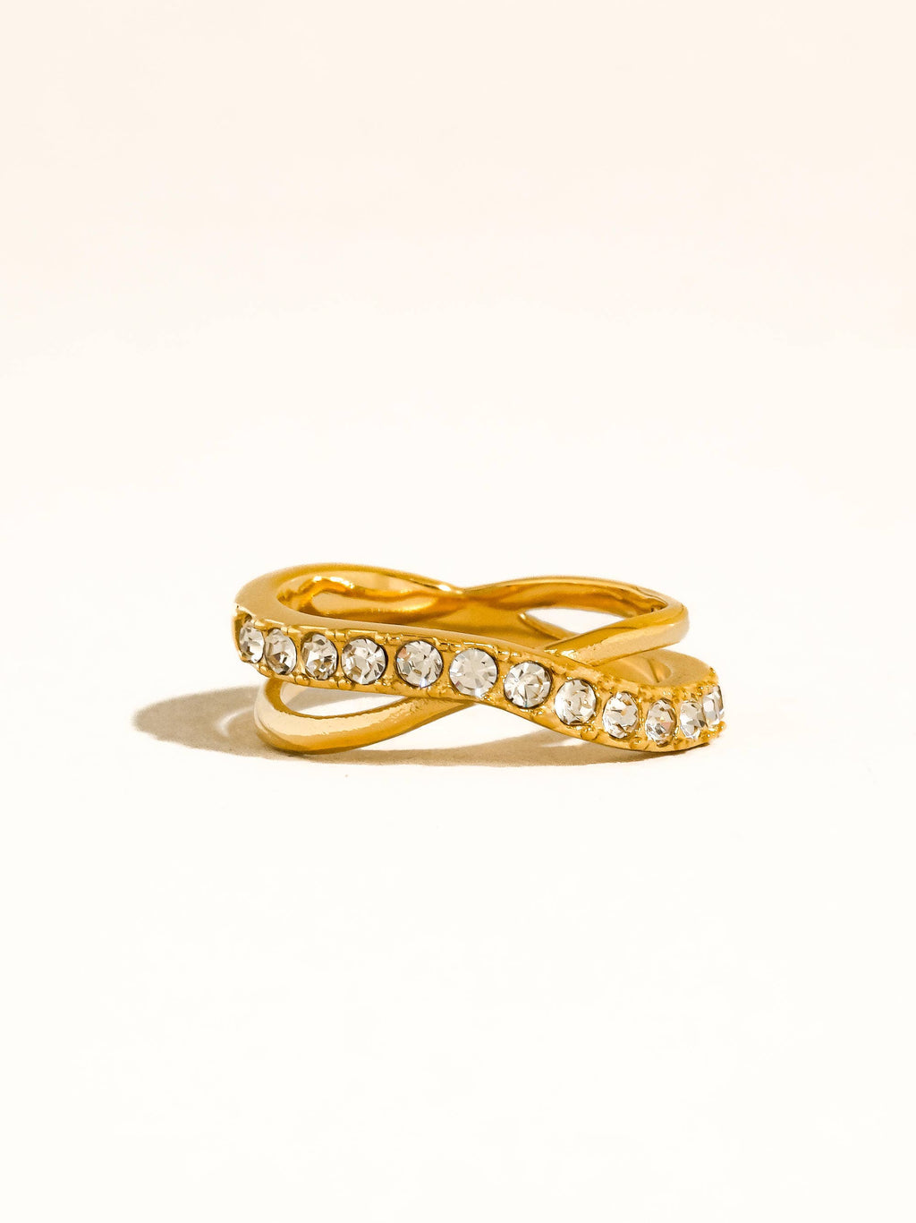 Gold tone crossover ring with CZ on a white background