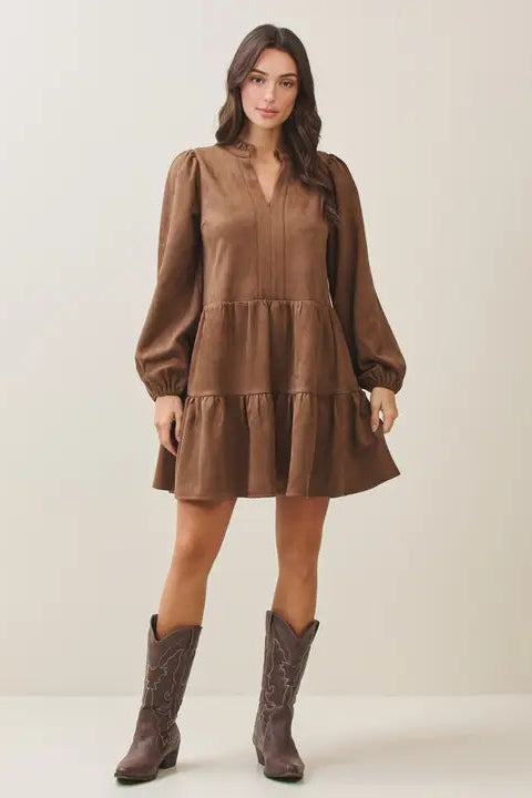 Woman wearing a mocha tiered dress and matching boots against a plain background