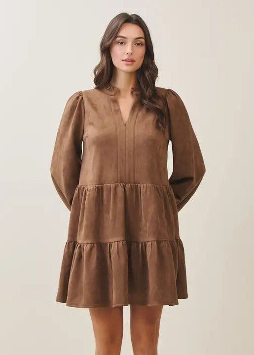 Woman wearing a mocha tiered dress against a plain background