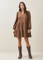 Woman wearing a mocha tiered dress and matching boots against a plain background