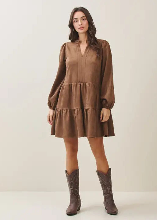 Woman wearing a mocha tiered dress and matching boots against a plain background