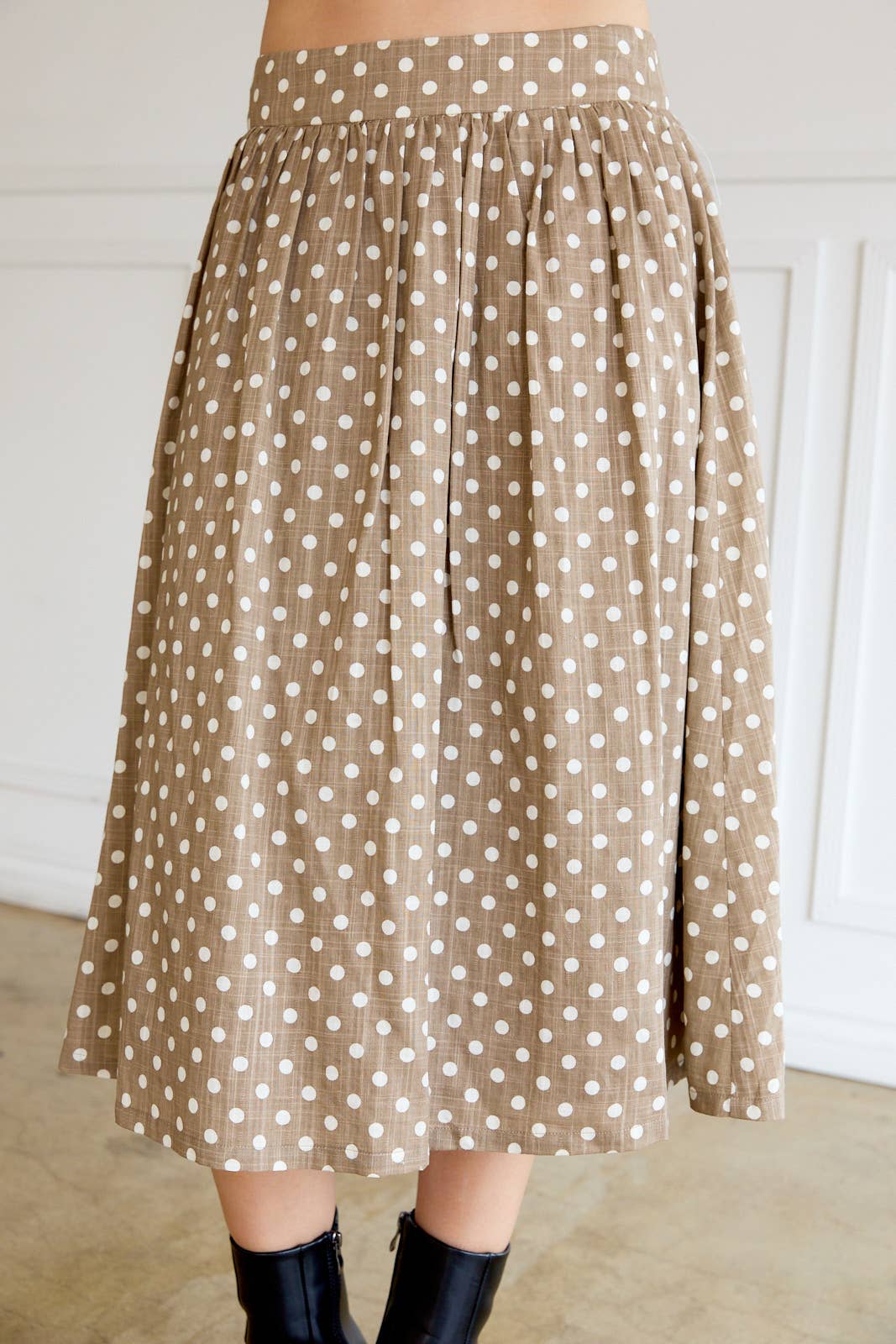 Woman wearing a tan polka dot skirt with cream dots