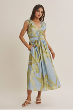 Woman wearing a sleeveless dress with a floral pattern on a plain background