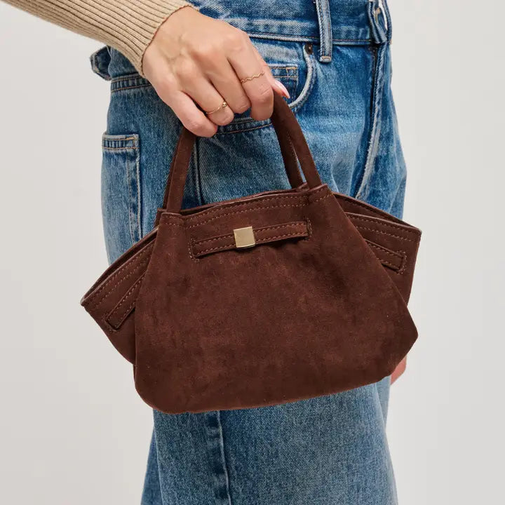 Chocolate handbag held by a person wearing blue jeans on a plain background