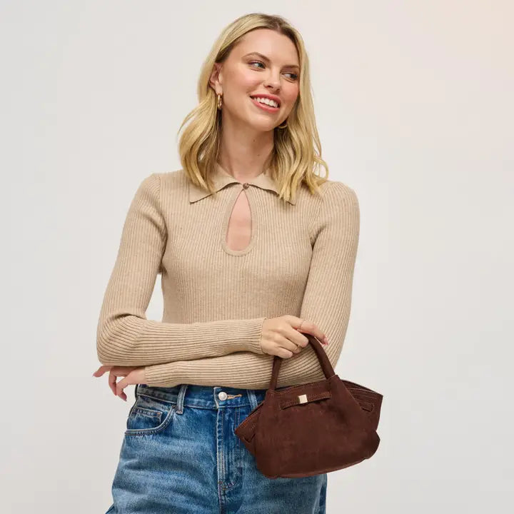 Woman holding chocolate handbag wearing blue jeans on a plain background