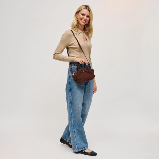 Woman holding chocolate handbag wearing blue jeans on a plain background