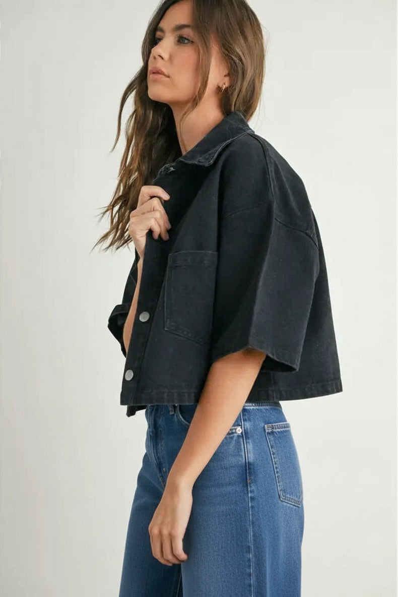 Woman wearing a black denim cropped top and denim on a white background