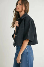 Woman wearing a black denim cropped top and denim on a white background