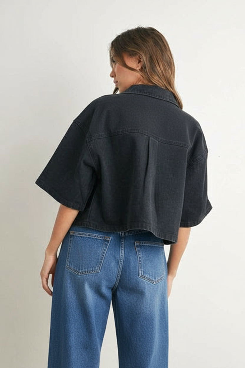 Person wearing a black denim cropped top and denim on a plain background